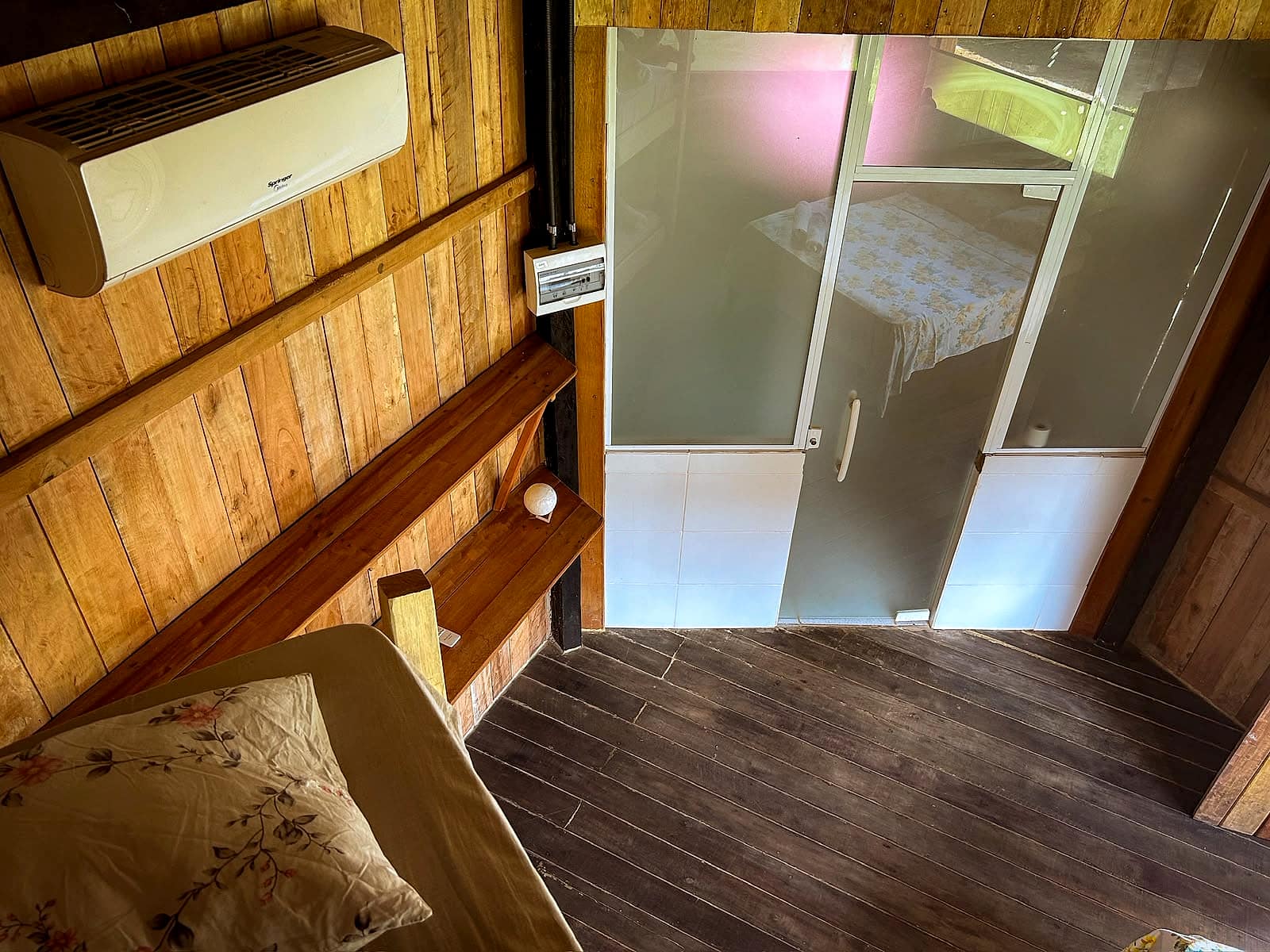 Detalhe do canto do quarto com ar-condicionado e porta do banheiro