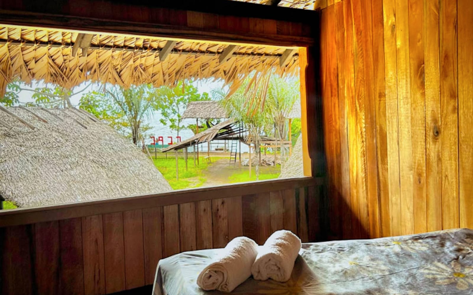 Cama de casal junto à ampla janela com vista para o terreno e a mata