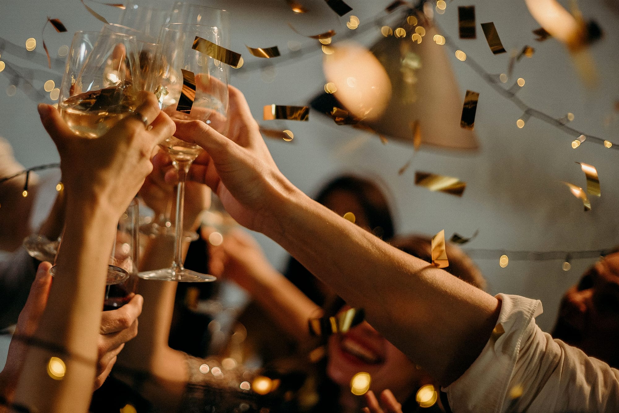 Amigos brindando com taças, entre confete dourado, na virada do ano