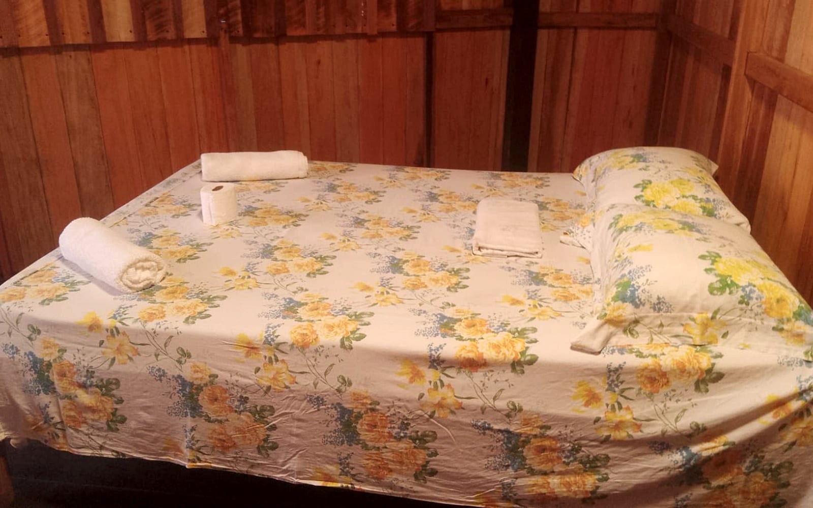 Cama de casal com colcha florida na Suíte Jurunas